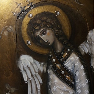 May include: A painting of an angel with white wings, a gold halo, and a white dress with gold accents. The angel has long brown hair and a sad expression.
