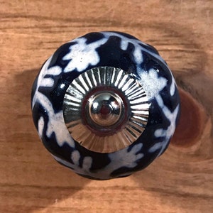 May include: A blue and white ceramic knob with a silver metal base. The knob has a floral pattern.
