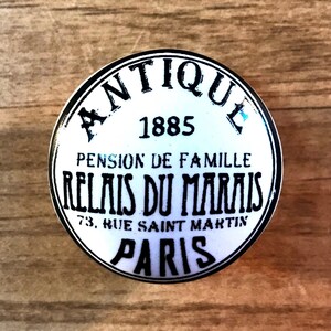 May include: White ceramic knob with black lettering that reads "Antique 1885 Pension de Famille Relais du Marais 73, Rue Saint Martin Paris".