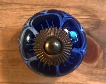 May include: Blue ceramic knob with a white floral design and a brass accent. The knob has a shiny finish.