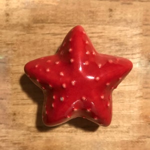 May include: A red ceramic starfish with a glossy finish and white dots.