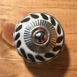 White ceramic sphere knob with black olive branch patter and silver steel stem...this is one of my favorite knobs. Has great texture.