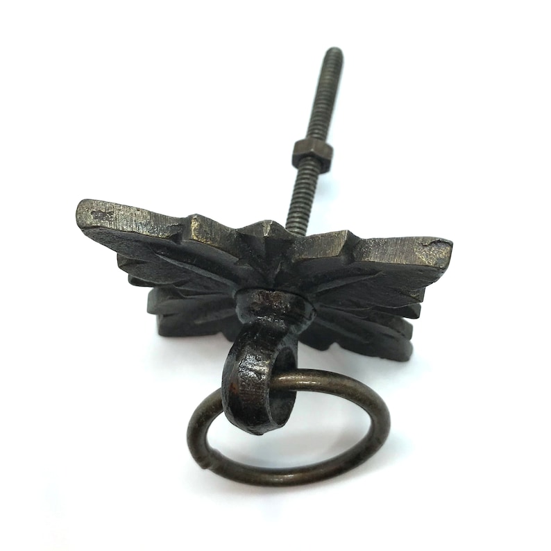 May include: A black metal cabinet knob with a decorative floral design and a ring pull. The knob has a threaded stem for mounting.