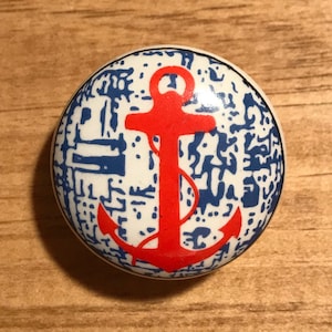 May include: A white ceramic knob with a red anchor design on a blue and white patterned background.