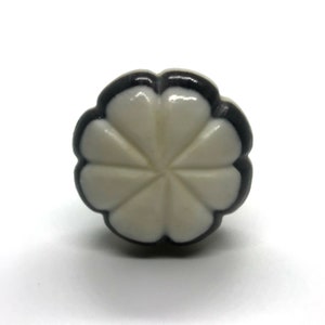 May include: White ceramic cabinet knob with a black border and a flower design.