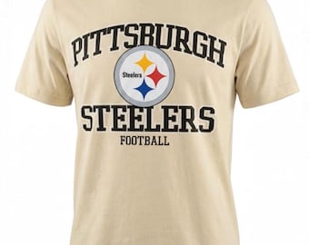 Peut inclure: Un t-shirt beige avec l'inscription "PITTSBURGH STEELERS FOOTBALL" en noir. Le logo des Steelers est au centre, avec un emblème jaune, rouge et bleu. Le t-shirt a un col rond et des manches courtes.