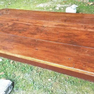 May include: A rectangular wooden table with a rich brown finish. The table has a slightly rounded edge and is supported by four dark brown legs. The table appears to be approximately 60 inches long.