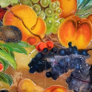 May include: A still life painting of fruit and grapes. The painting features peaches, cherries, and grapes in shades of red, green, yellow, and purple. The fruit is arranged on a wooden surface with green leaves.