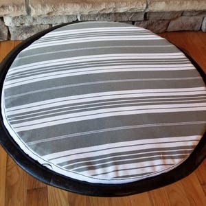 May include: A round gray and white striped pet bed with a black wooden frame.