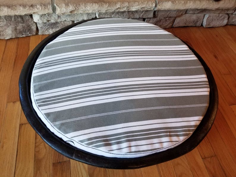 May include: A round gray and white striped pet bed with a black wooden frame.