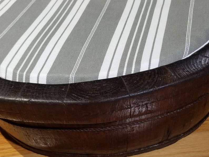 May include: A round, dark brown wooden ottoman with a gray and white striped fabric top.