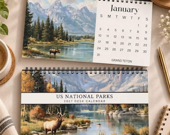Puede incluir: Un calendario de escritorio 2027 titulado US National Parks con encuadernación en espiral. La página superior muestra el mes de enero con un paisaje de Grand Teton y un alce. La página inferior muestra un uapití en un lago.