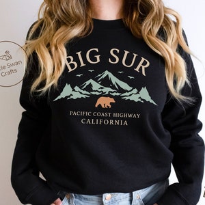 May include: Black sweatshirt with a graphic design of mountains, a bear, and the text "BIG SUR PACIFIC COAST HIGHWAY CALIFORNIA".
