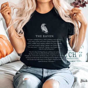 Puede incluir: Camiseta negra con una ilustraci&oacute;n de cuervo blanco y texto del poema "El Cuervo" de Edgar Allan Poe. El texto dice: "Once upon a midnight dreary, while I pondered, weak and weary. Over many a quaint and curious volume of forgotten lore - While I nodded, nearly napping, suddenly there came a tapping. As of some one gently rapping, rapping at my chamber door - "Tis some visitor," I muttered, "tapping at my chamber door - Only this and nothing more."