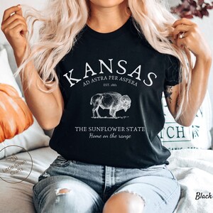 May include: Black t-shirt with white text that reads "Kansas, Ad Astra Per Aspera, Est. 1861, The Sunflower State, Home on the Range". A vintage illustration of a buffalo is above the text.