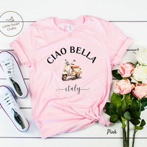 Pu&ograve; includere: Maglietta rosa con un'immagine di uno scooter vintage e il testo "Ciao Bella - italy".