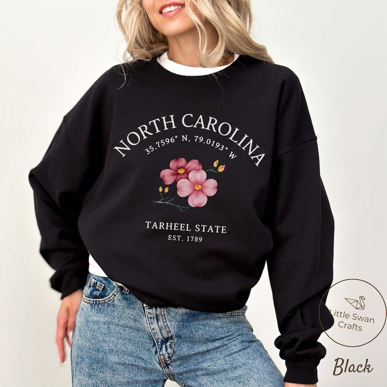 May include: Black sweatshirt with the text "NORTH CAROLINA" and coordinates, floral graphic, and "TARHEEL STATE EST. 1789". The sweatshirt is a crew neck style.
