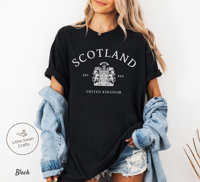 Pode incluir: T-shirt preto com a palavra "SCOTLAND" em branco, em arco, um bras&atilde;o e as palavras "EST. 843" e "UNITED KINGDOM". A t-shirt tem um estilo casual.