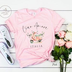 May include: Pink t-shirt with a graphic of a vintage scooter with the text "Ciao Amore" and "ITALIA" printed on it.