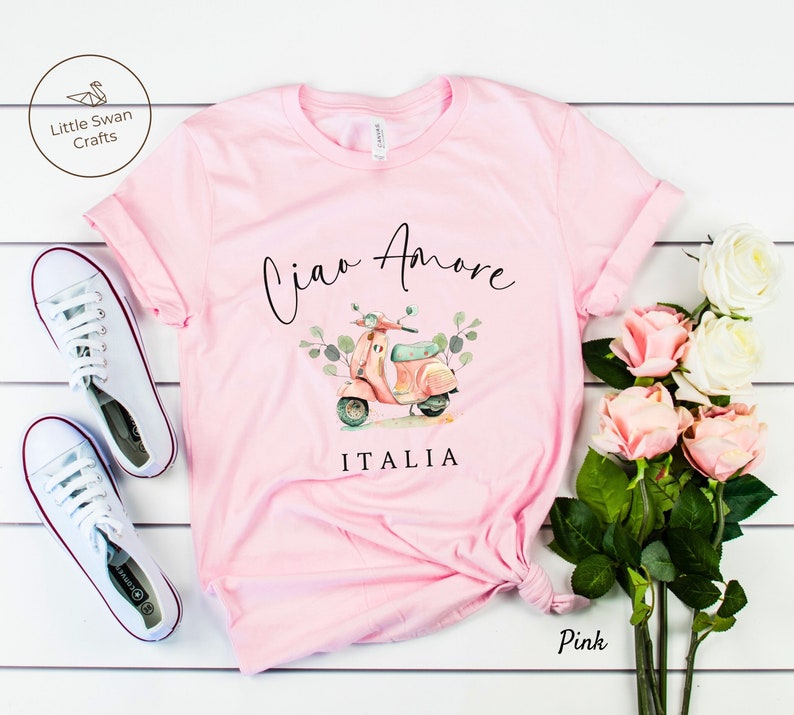 May include: Pink t-shirt with a graphic of a vintage scooter with the text "Ciao Amore" and "ITALIA" printed on it.