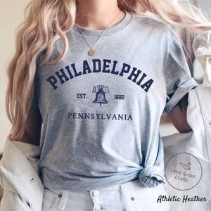 May include: Gray t-shirt with a blue graphic of the Liberty Bell and the text "PHILADELPHIA EST. 1682 PENNSYLVANIA".