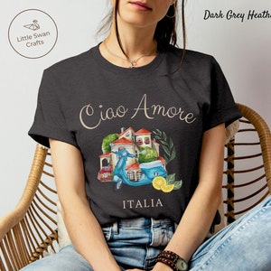 May include: Dark grey heather t-shirt with a watercolor illustration of a scooter, a small house, and lemons. The text "Ciao Amore" and "ITALIA" are printed on the shirt.