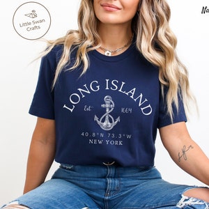 Op de afbeelding: Donkerblauw T-shirt met een witte anker afbeelding en de tekst "LONG ISLAND Est. 1664 40.8&deg;N 73.3&deg;W NEW YORK"