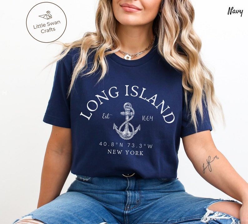 Op de afbeelding: Donkerblauw T-shirt met een witte anker afbeelding en de tekst "LONG ISLAND Est. 1664 40.8&deg;N 73.3&deg;W NEW YORK"