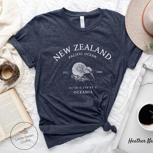Peut inclure: T-shirt bleu marine chin&eacute; avec un motif blanc d'un kiwi et le texte "NEW ZEALAND PACIFIC OCEAN EST. 1840 41&deg;18&prime;S 174&deg;47&prime;E OCEANIA"