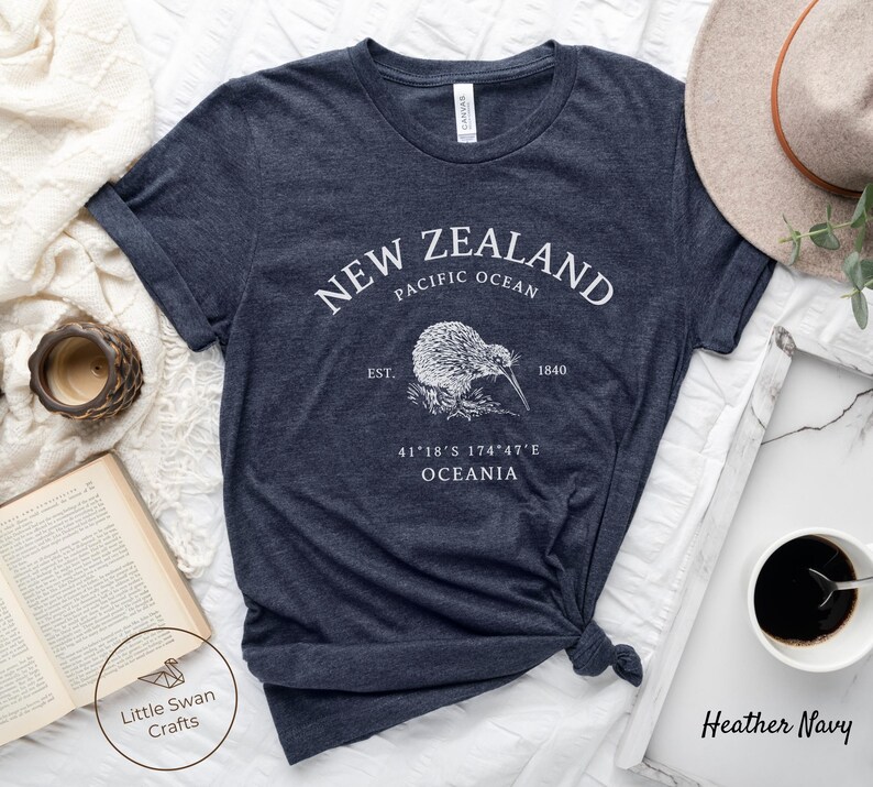 Peut inclure: T-shirt bleu marine chin&eacute; avec un motif blanc d'un kiwi et le texte "NEW ZEALAND PACIFIC OCEAN EST. 1840 41&deg;18&prime;S 174&deg;47&prime;E OCEANIA"