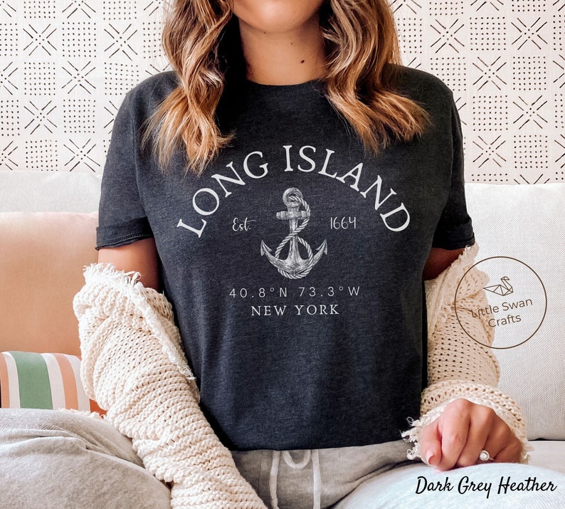 Op de afbeelding: Donkergrijs heather t-shirt met een wit grafisch ontwerp van een anker en de tekst "LONG ISLAND Est 1664 40.8&deg;N 73.3&deg;W NEW YORK".
