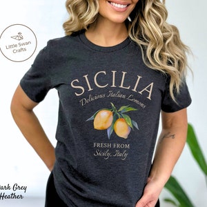Peut inclure: T-shirt en jersey gris fonc&eacute; chin&eacute; avec un motif graphique repr&eacute;sentant des citrons et le texte "SICILIA Delicious Italian Lemons FRESH FROM Sicily, Italy".