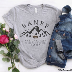 May include: Gray t-shirt with a black graphic design of a mountain range, a moose, and the text "Banff National Park, Alberta's Rockies, Canada".