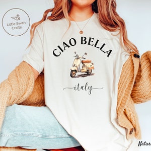 Pu&ograve; includere: Maglietta bianca con una grafica nera di uno scooter vintage e il testo "Ciao Bella - italy".