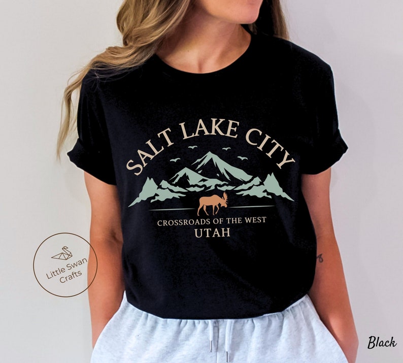 May include: Black t-shirt with a graphic design featuring the text "Salt Lake City, Crossroads of the West, Utah" with a mountain range and a moose silhouette.