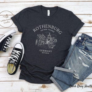 Pode incluir: Camiseta cinza escuro heather com um gr&aacute;fico branco da cidade de Rothenburg ob der Tauber, Alemanha. O texto "Rothenburg ob der Tauber, Alemanha, Baviera" est&aacute; impresso na camiseta.