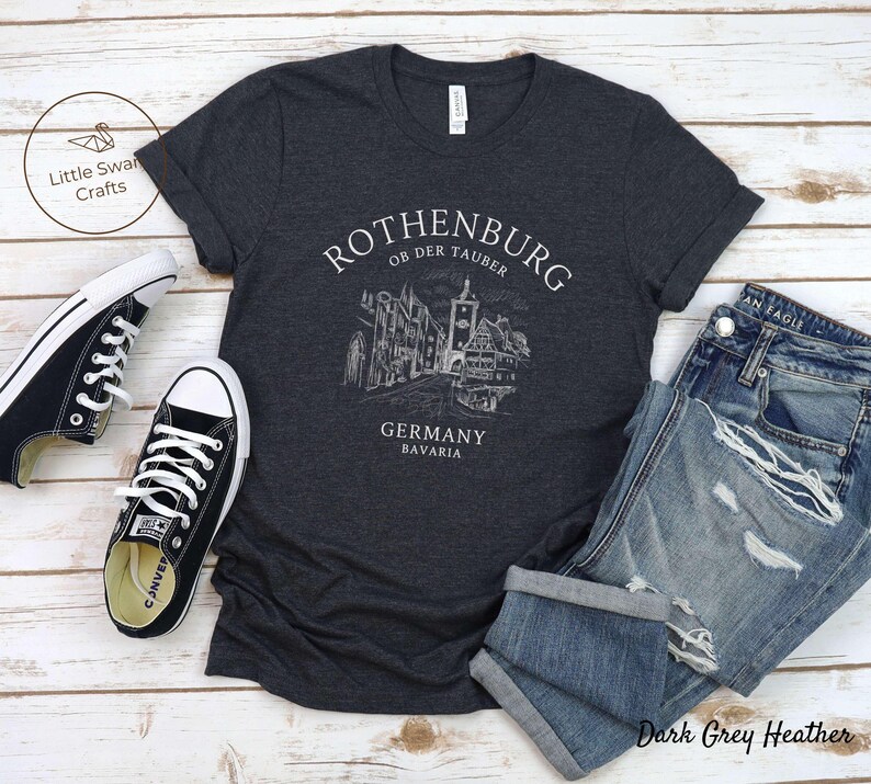Pode incluir: Camiseta cinza escuro heather com um gr&aacute;fico branco da cidade de Rothenburg ob der Tauber, Alemanha. O texto "Rothenburg ob der Tauber, Alemanha, Baviera" est&aacute; impresso na camiseta.