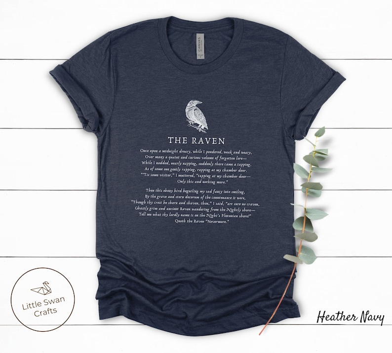 Puede incluir: Camiseta azul marino jaspeado con una ilustraci&oacute;n de cuervo blanco y texto del poema "El Cuervo" de Edgar Allan Poe. El texto dice: "Once upon a midnight dreary, while I pondered, weak and weary..."