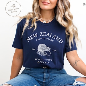 Peut inclure: T-shirt bleu marine avec un graphique blanc d'un kiwi et le texte "NEW ZEALAND, PACIFIC OCEAN, EST. 1840, 41&deg;18&prime;S 174&deg;47&prime;E, OCEANIA".