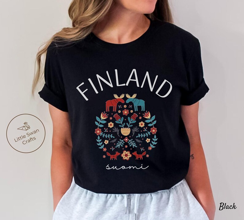 May include: Black t-shirt with a white graphic design featuring the word "FINLAND" in a stylized font, a floral pattern, two moose, and the word "suomi" in a script font.