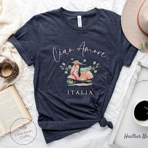 May include: A heather navy blue t-shirt with a pink scooter graphic and the text "Ciao Amore ITALIA" in a pink script font.