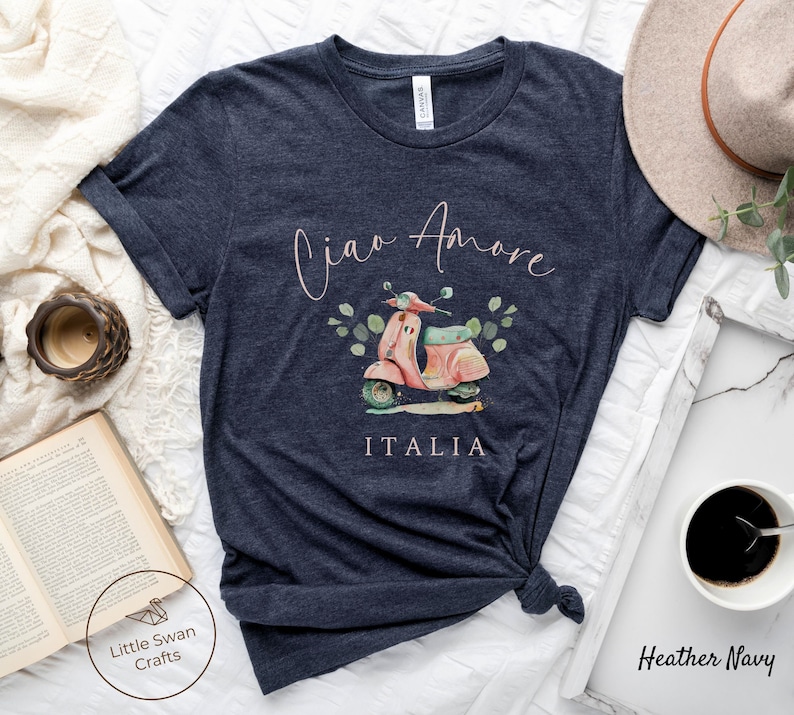May include: A heather navy blue t-shirt with a pink scooter graphic and the text "Ciao Amore ITALIA" in a pink script font.