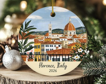 Puede incluir: Un adorno de cerámica redondo con una ilustración pintada del horizonte de Florencia con el Duomo, tejados de terracota y plantas en macetas. La parte inferior es de color crema con el texto Florence, Italy y el año 2026.