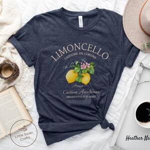 May include: A heather navy blue t-shirt with a vintage-style illustration of lemons and flowers. The text "Limoncello Liqoure de Limone Fresco Costiera Amalfitana Prodotto Italiano" is printed on the shirt.
