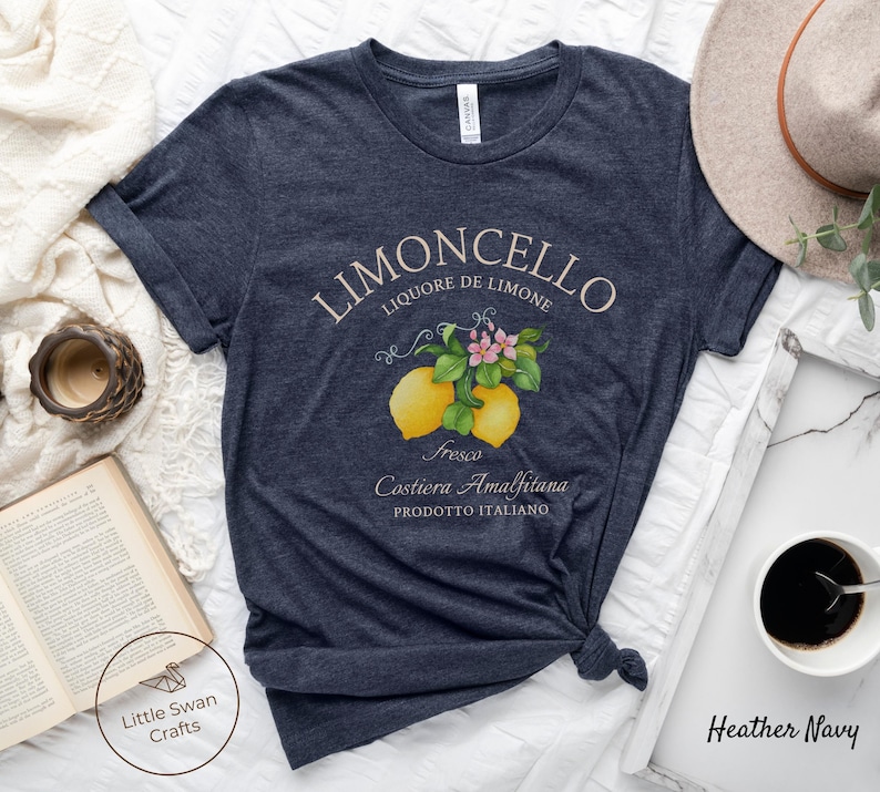 May include: A heather navy blue t-shirt with a vintage-style illustration of lemons and flowers. The text "Limoncello Liqoure de Limone Fresco Costiera Amalfitana Prodotto Italiano" is printed on the shirt.