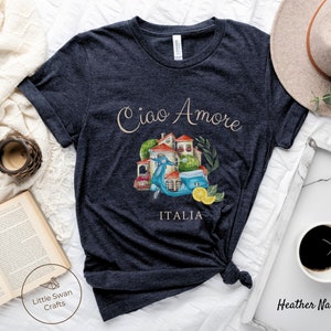 May include: Heather navy blue t-shirt with a watercolor illustration of a scooter, a building, and lemons. The text "Ciao Amore" and "ITALIA" are printed on the shirt.