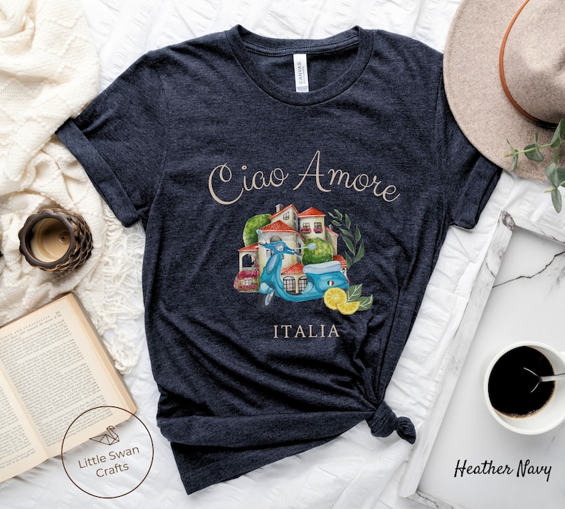 May include: Heather navy blue t-shirt with a watercolor illustration of a scooter, a building, and lemons. The text "Ciao Amore" and "ITALIA" are printed on the shirt.