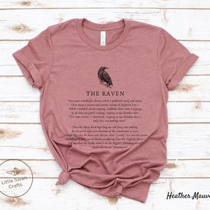Puede incluir: Una camiseta de color malva brezo con una ilustraci&oacute;n en blanco y negro de un cuervo y el texto "THE RAVEN" y la primera estrofa del poema "El Cuervo" de Edgar Allan Poe.