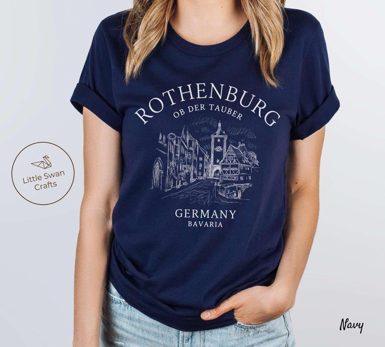 Pode incluir: Camiseta azul marinho com um gr&aacute;fico branco do horizonte de Rothenburg ob der Tauber, Alemanha. O texto "Rothenburg ob der Tauber, Alemanha, Baviera" est&aacute; impresso na camiseta.