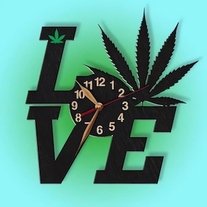 Pu&ograve; includere: Orologio da parete in legno nero a forma della parola "LOVE" con un design a foglia di marijuana e un quadrante dell'orologio al centro. Le lancette dell'orologio sono dorate e rosse.